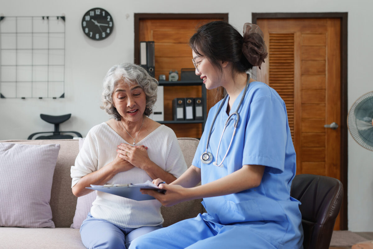 Asian youthful nurse caring for an elderly woman at home.